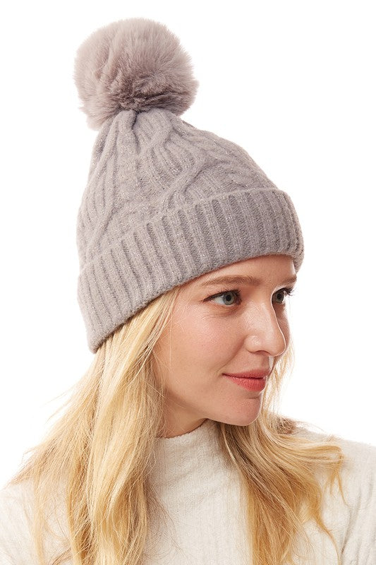 Women's Cable Knitted Lurex Beanie with a faux fur pom pom, showcasing a stylish cable knit pattern in a cozy design.