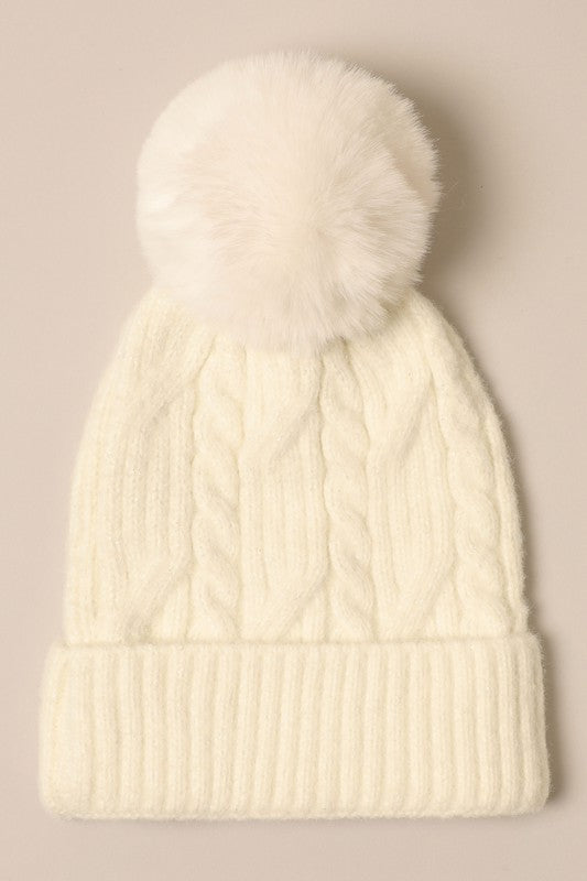 Women's Cable Knitted Lurex Beanie with a faux fur pom pom, showcasing a stylish cable knit pattern in a cozy design.