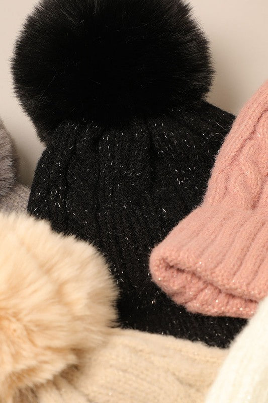 Women's Cable Knitted Lurex Beanie with a faux fur pom pom, showcasing a stylish cable knit pattern in a cozy design.