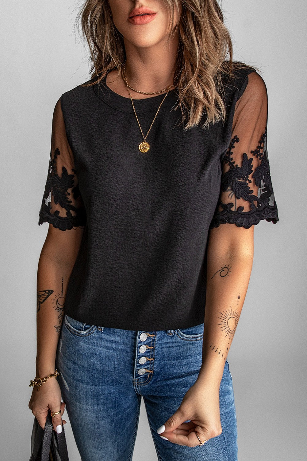 Women's black T-shirt with transparent lace sleeves, featuring a round collar and loose fit, perfect for casual and elegant occasions.
