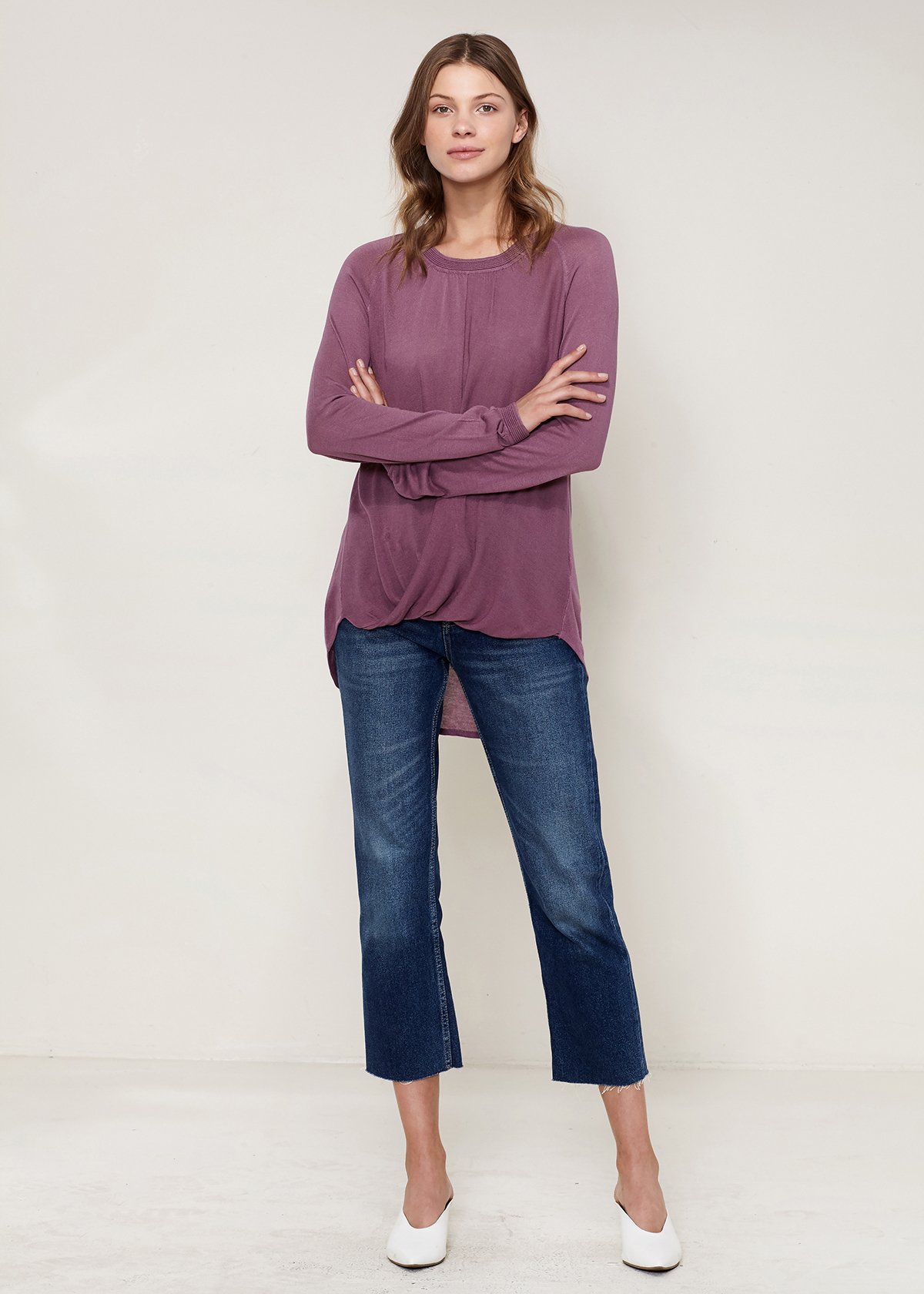 Woman wearing purple top and jeans.