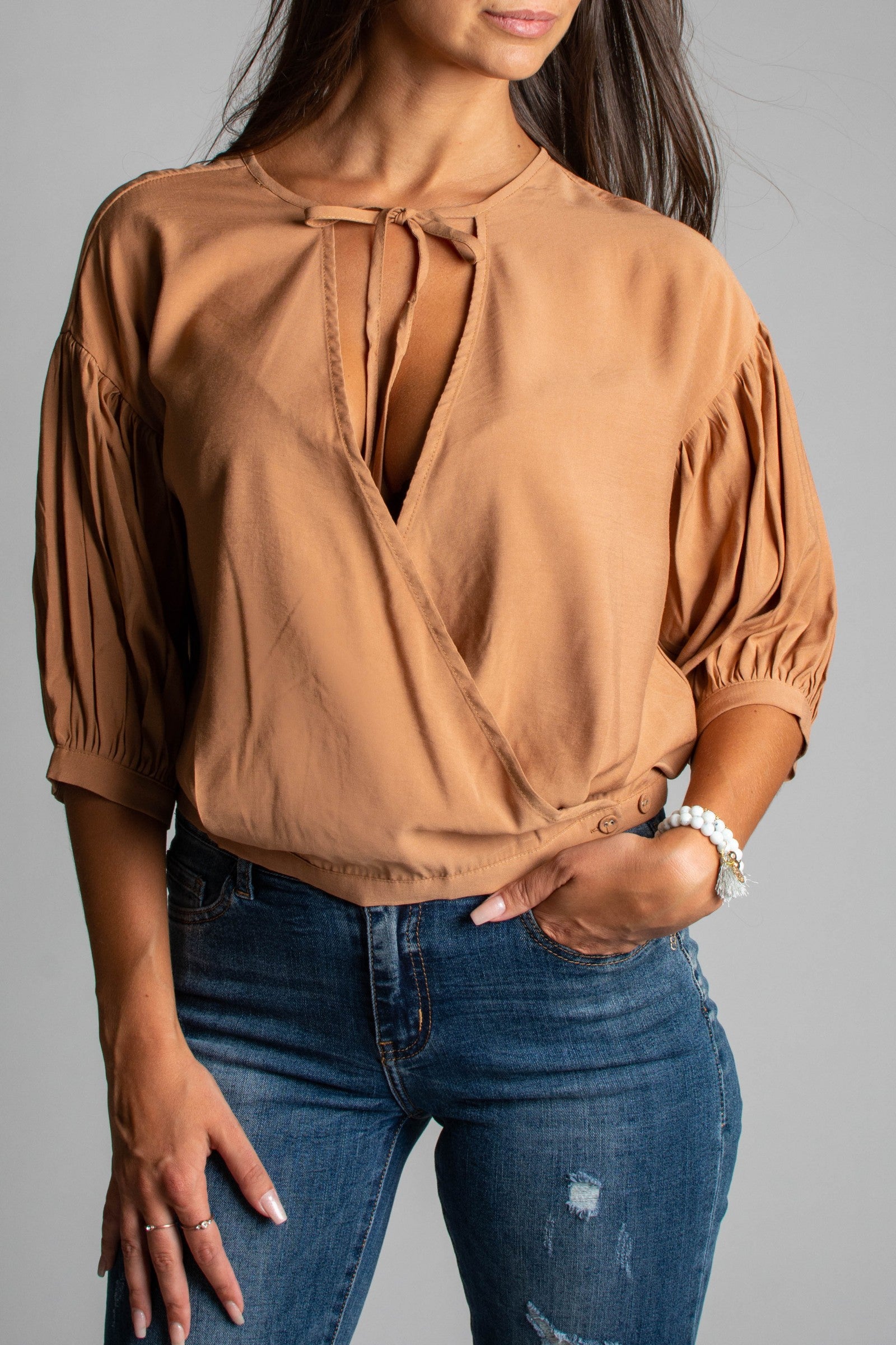 Khaki wrap blouse with short gathered sleeves and tie detail at décolleté, showcasing elegant design and high-quality fabric.