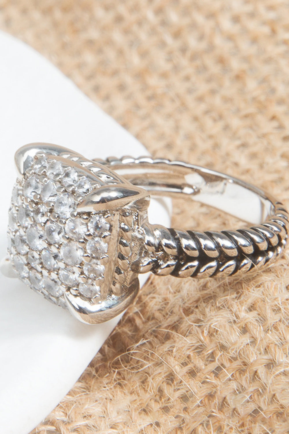 Zircon Twisted Ring featuring a minimalist design, crafted from zircon and copper with an 18k platinum-plated finish, displayed in a flat lay style.